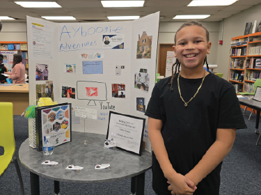 student standing next to trifold poster board